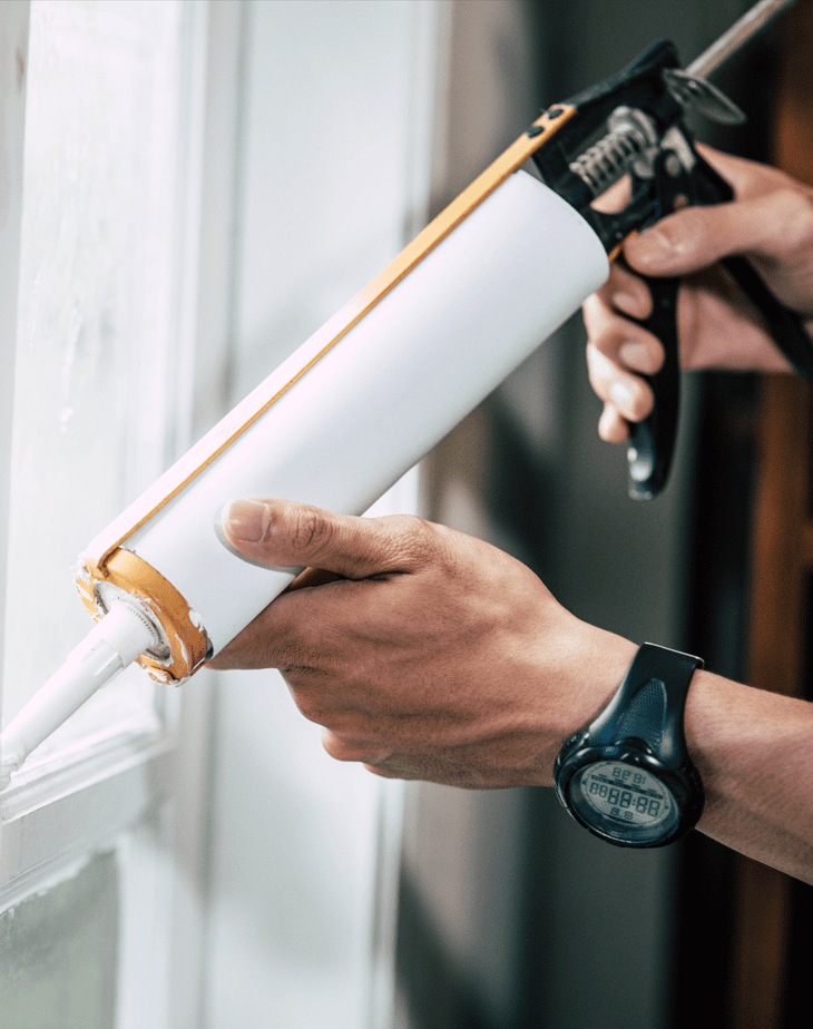 Worker sealing a shower pan with silicone sealant to prevent leaks and ensure a watertight seal.