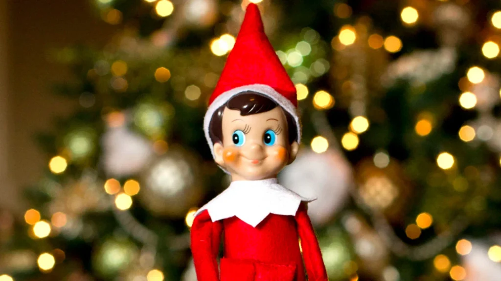 Elf on the Shelf sitting in a playful pose on a bathroom counter