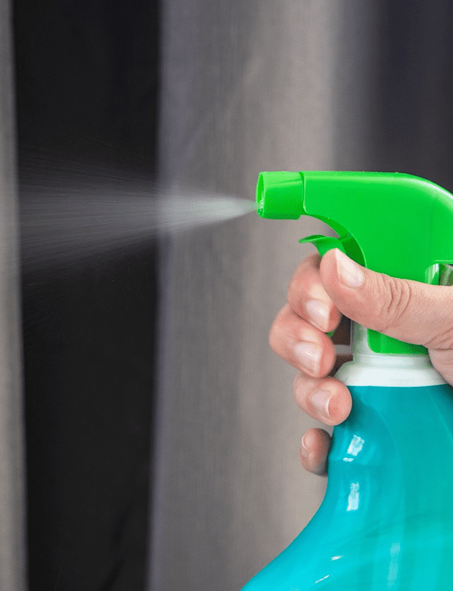 Hand spraying cleaning products for bathroom floor and glass.